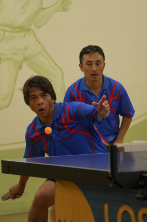 Gerry Chua sets up to rip a forehand loop as doubles teammate June Lim watches in anticipation